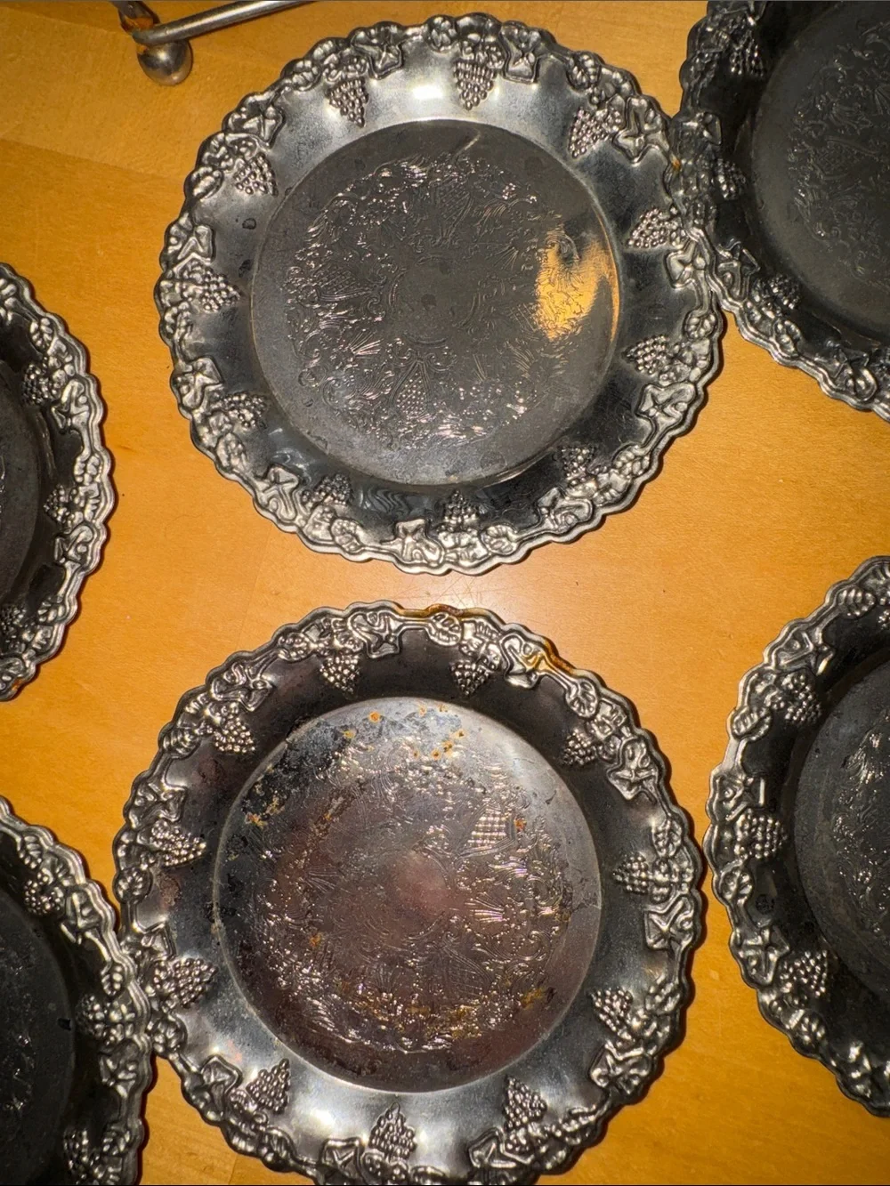 six vintage silver-plated drink coasters with ornate, embossed floral